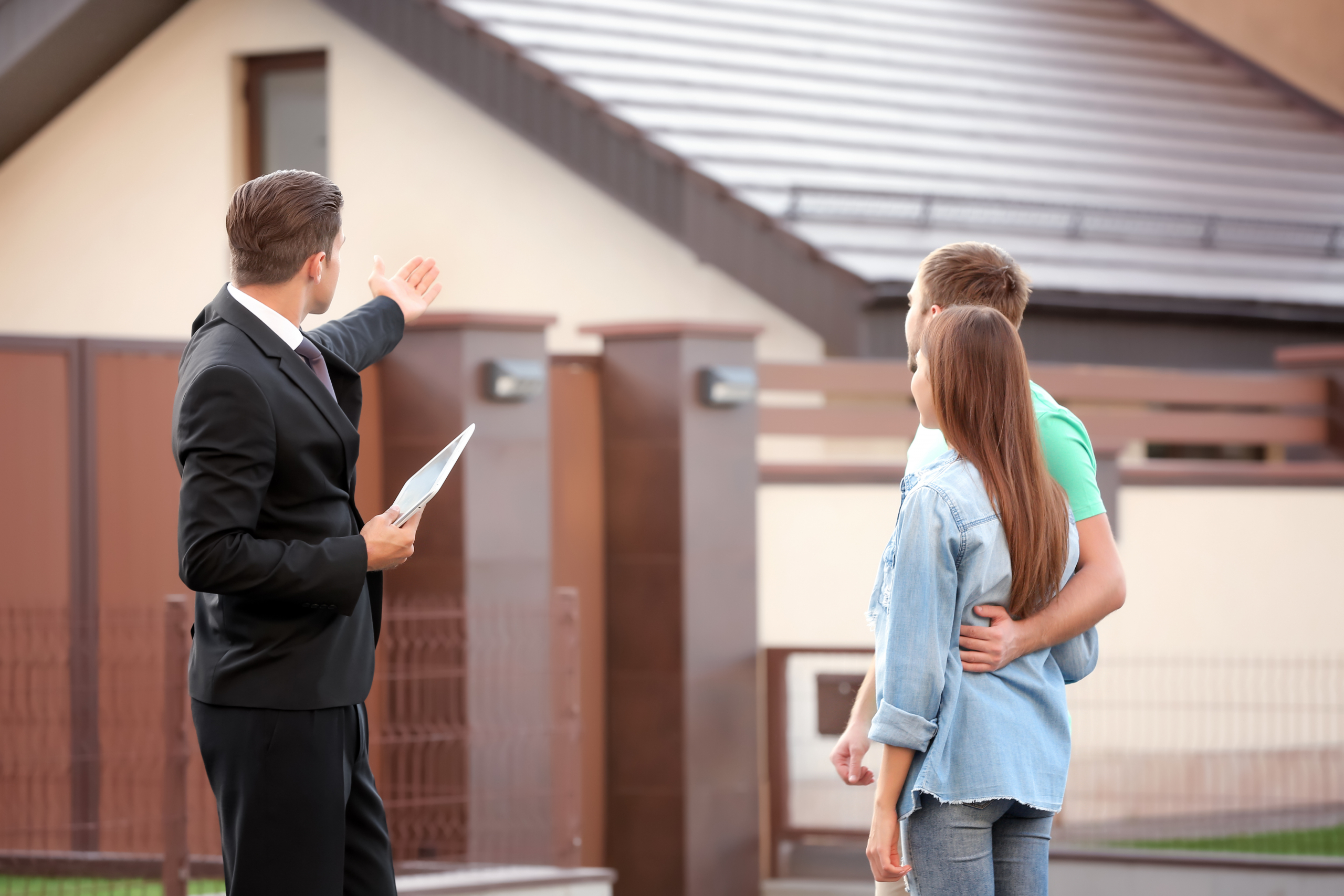Paar mit Immobilienmakler vor ihrem Haus in Oberschwaben